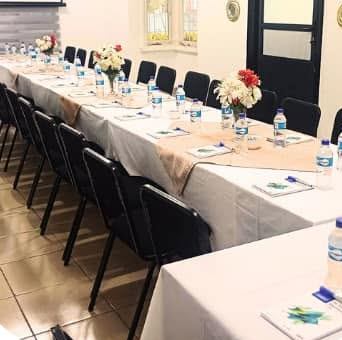 Long white-clothed tables with water bottles and notepads set for a meeting
